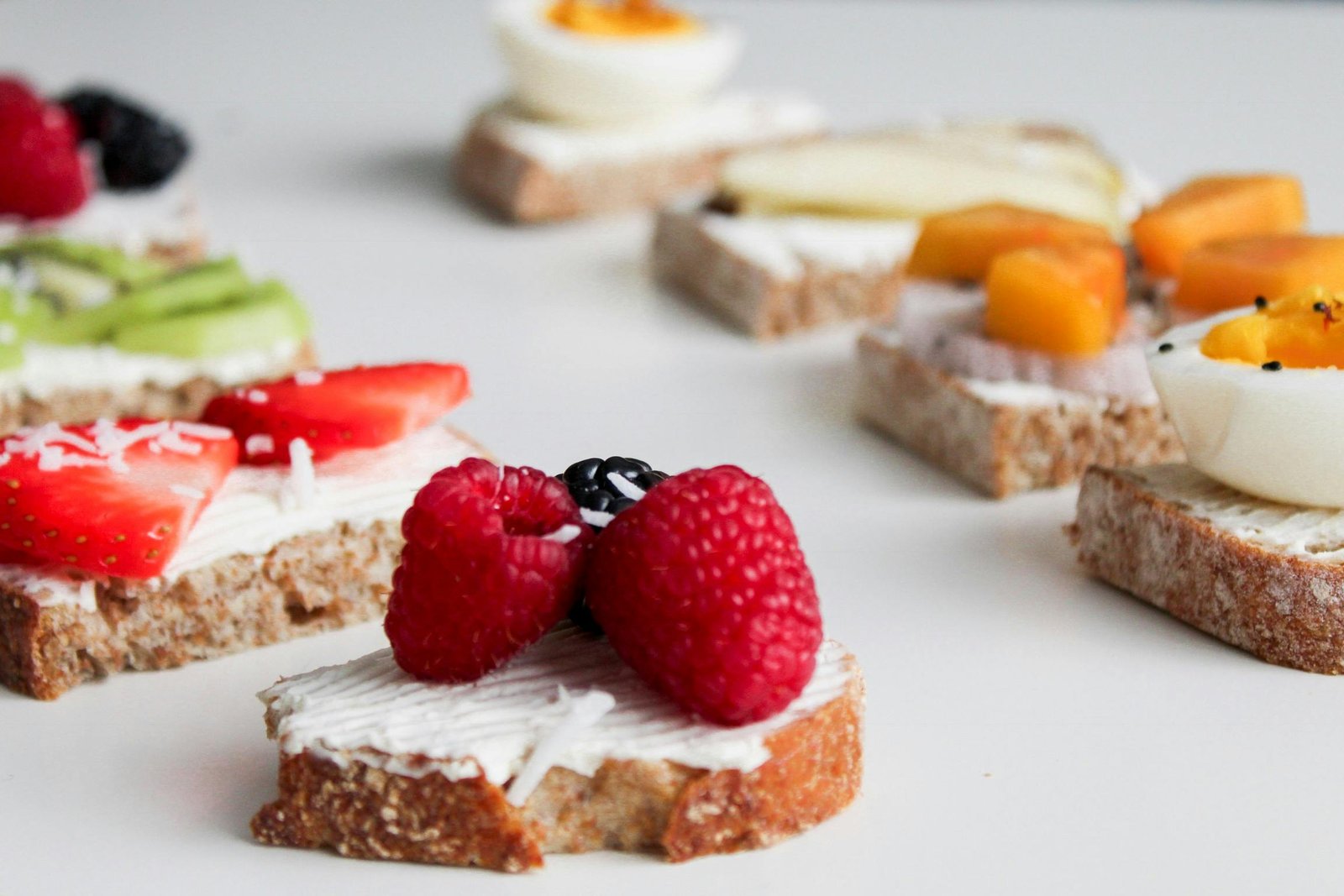 A delicious variety of open-faced sandwiches with creamy toppings, fresh fruits, and eggs.