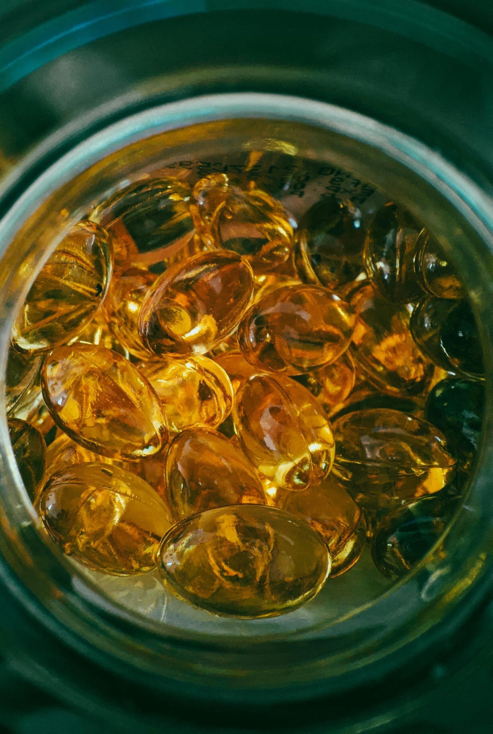 Close-up top view of transparent golden capsules inside an open jar, showcasing healthy supplements.